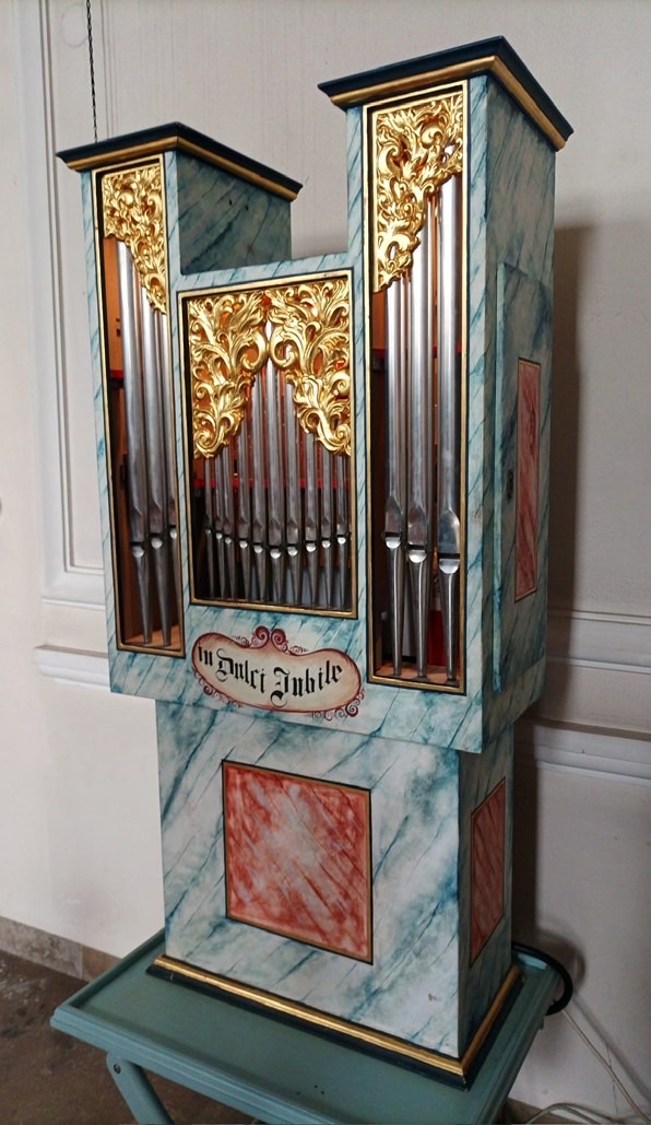 Eine kleine Orgel an der Wand, in die man eine Münze einwerfen kann